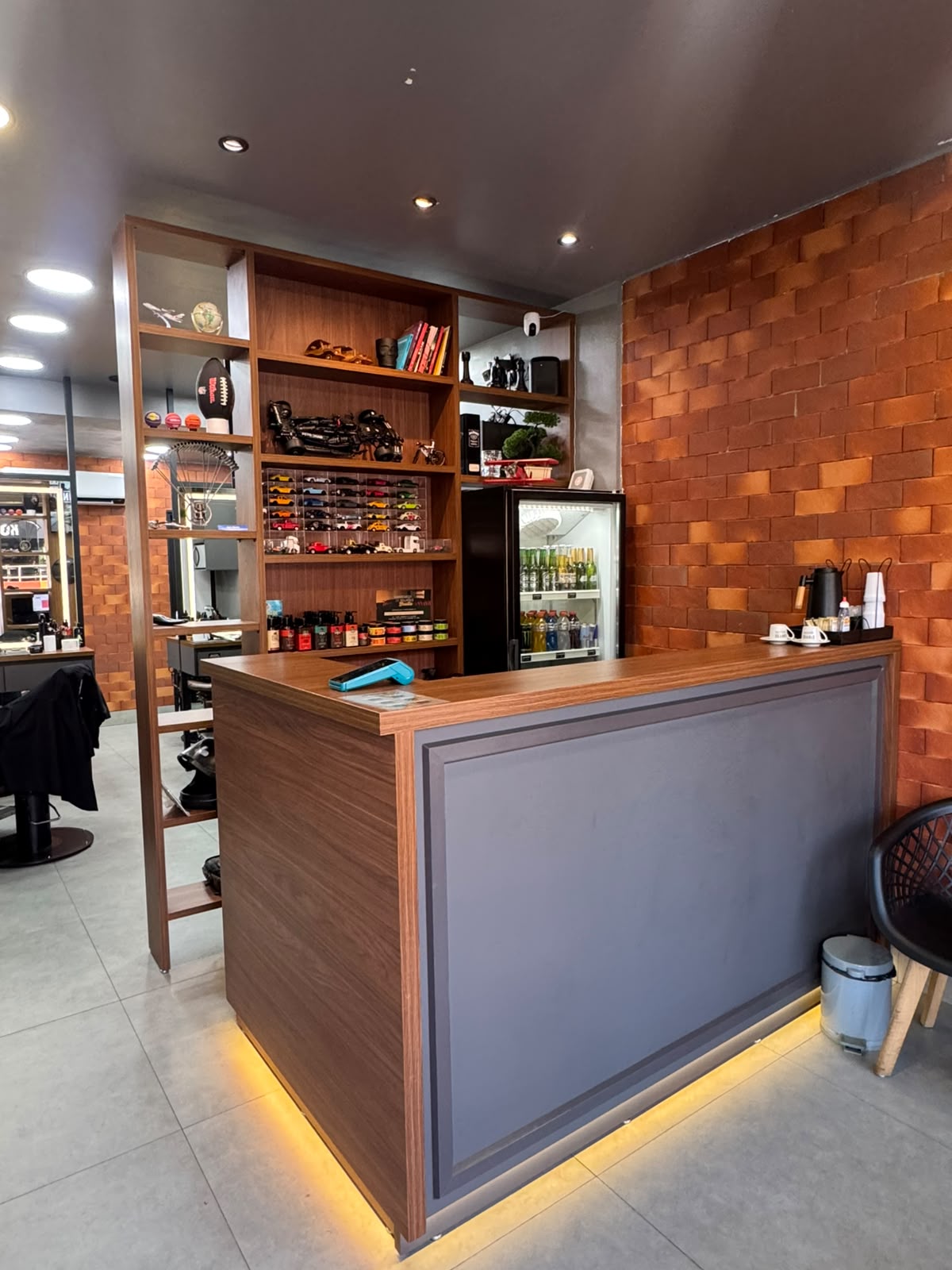 Interior da barbearia O Legado, com balcão de madeira e parede de tijolinhos